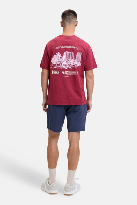 Blauwe short van JACK & JONES JEANS INTELLIGENCE, gedragen door een man met een bordeauxrood T-shirt met witte print en beige sneakers, van achteren gezien.
