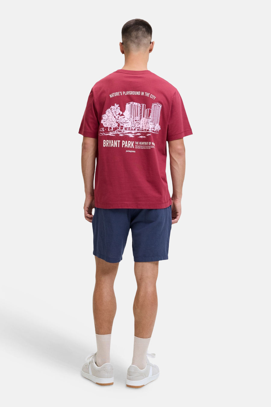Blauwe short van JACK & JONES JEANS INTELLIGENCE, gedragen door een man met een bordeauxrood T-shirt met witte print en beige sneakers, van achteren gezien.