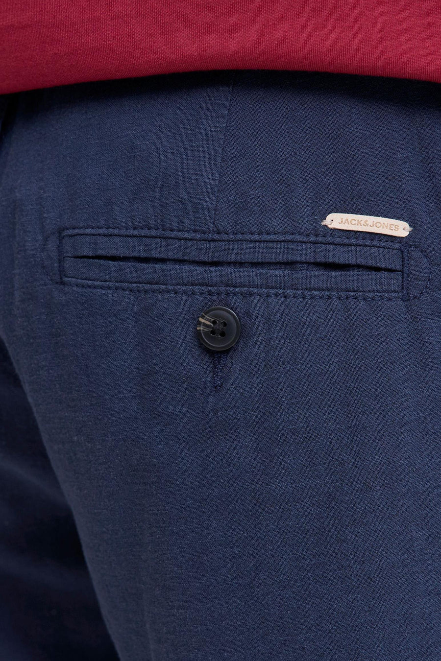 Blauwe short van geweven stof van JACK & JONES JEANS INTELLIGENCE met achterzak, knoop en lichtbruin label, erboven een rood T-shirt.