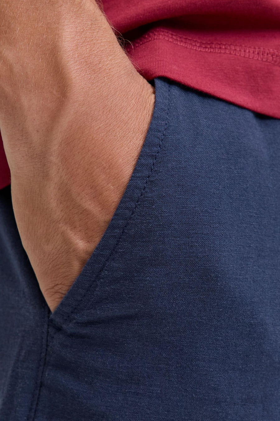 Blauwe short van JACK & JONES JEANS INTELLIGENCE met linnenlook textuur, hand in zak en rood shirt.