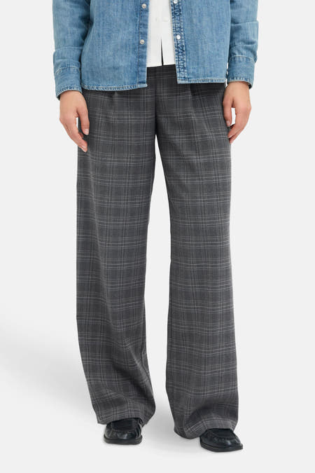 Grijze kostuumbroek van JJXX, met een ruitpatroon, gecombineerd met een denim overhemd en wit shirt.