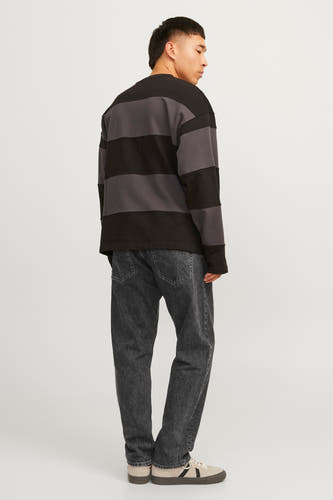 Jean délavé noir de JACK & JONES JEANS INTELLIGENCE, porté avec un pull rayé et des baskets basses.