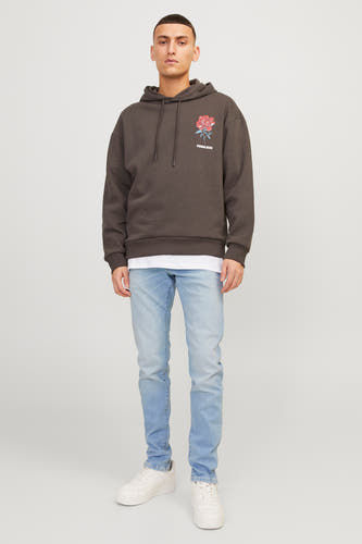 Lichtblauwe slim fit jeans van JACK & JONES JEANS INTELLIGENCE, gecombineerd met een bruine hoodie en witte sneakers.
