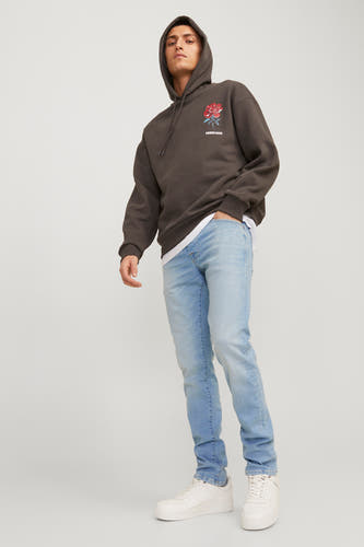Lichtblauwe slim jeans van JACK & JONES JEANS INTELLIGENCE, gecombineerd met witte sneakers en een bruine hoodie.