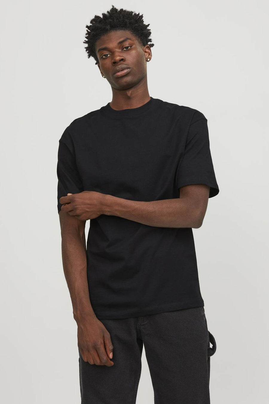 T-shirt noir à manches courtes de ORIGINALS BY JACK & JONES, porté avec un pantalon foncé.