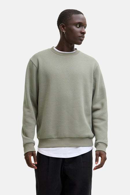 Groene sweater met ronde hals van CORE BY JACK & JONES, gedragen over een wit T-shirt en een zwarte broek.