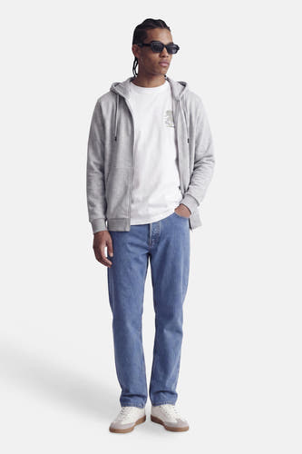 Grijze zip hoodie van CORE BY JACK & JONES, met capuchon en voorzak, gedragen over wit T-shirt, blauwe jeans en witte sneakers, front view.