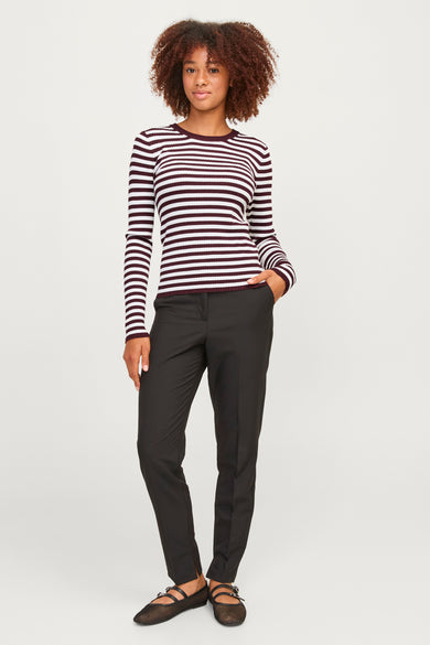 Rode T-shirt met lange mouwen van JJXX, met horizontale witte strepen, gecombineerd met zwarte pantalon en nette platte schoenen.
