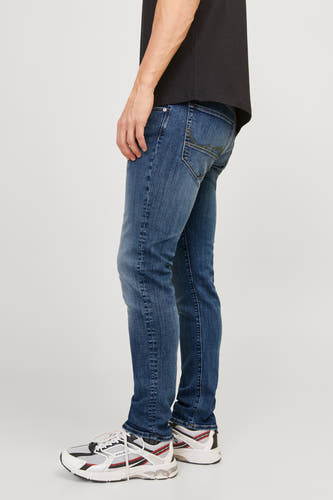 Jean slim fit denim bleu moyen de JACK & JONES, avec des boutons sur les poches arrière et des baskets blanches.