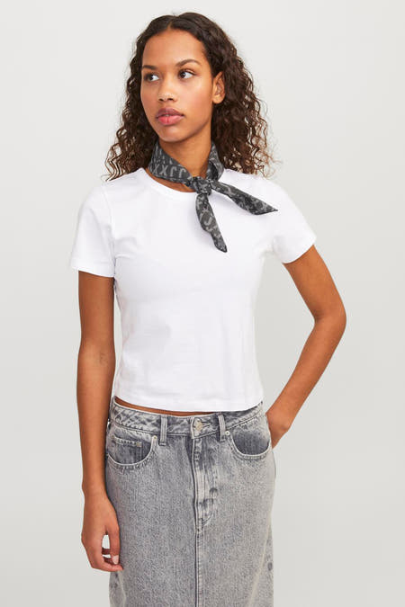 Zwarte zomersjaal van JJXX, gedragen als halsdoek, gecombineerd met een wit T-shirt en grijze jeans.
