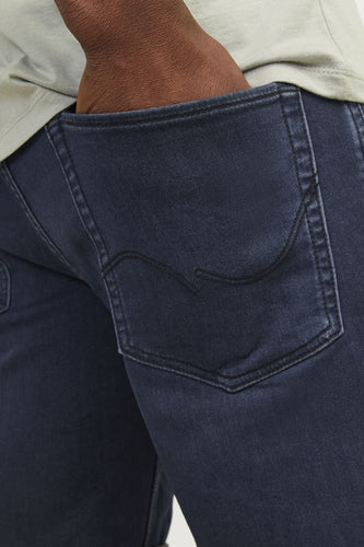 Close-up van een persoon in blauwe jeans met een hand in de achterzak.