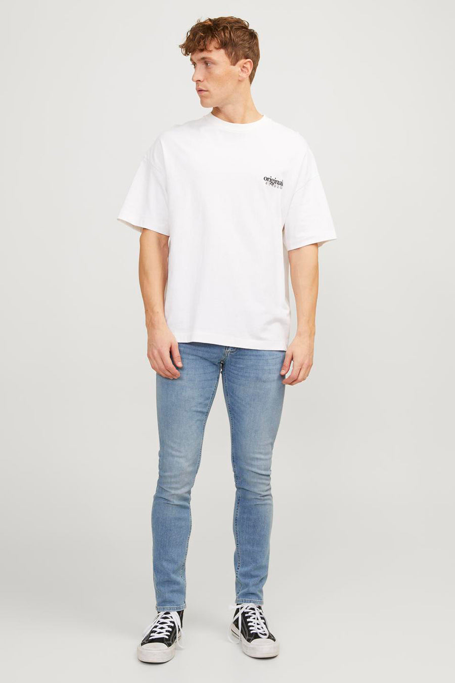 Lichtblauwe skinny jeans van JACK & JONES JEANS INTELLIGENCE, gecombineerd met een wit T-shirt en zwarte sneakers.