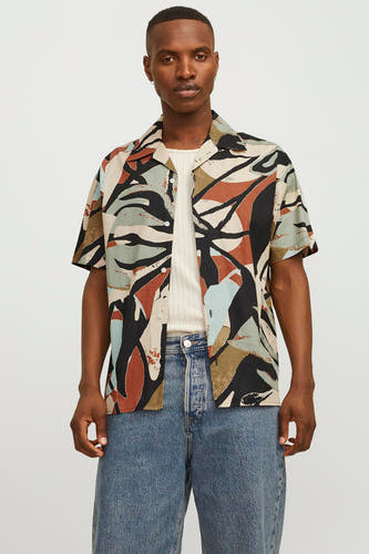 Chemise noire à manches courtes d'ORIGINALS BY JACK & JONES, avec un motif abstrait, portée sur un chemis blanc et des jeans.