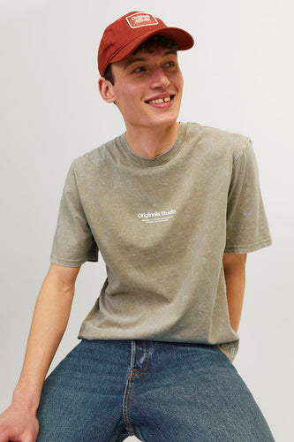 Man met rode pet, groen gevlekt T-shirt en blauwe jeans.