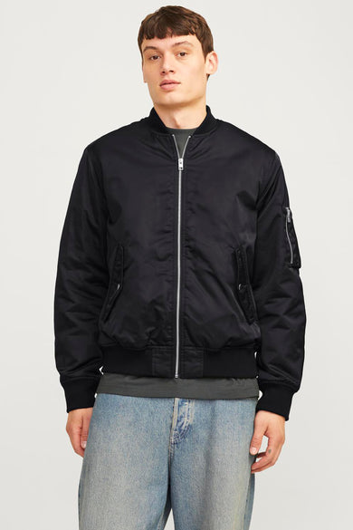 Blouson aviateur noir de CORE BY JACK & JONES, avec fermeture éclair argentée, poches et détail sur la manche, porté par un mannequin en jean bleu clair.