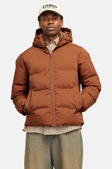 Bruine gewatteerde jas van CORE BY JACK & JONES, met capuchon, over een geruit overhemd en vintage jeans.