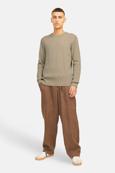 Beige pull met ronde hals van CORE BY JACK & JONES, met lange mouwen en gedragen met bruine linnen broek en crèmekleurige schoenen.
