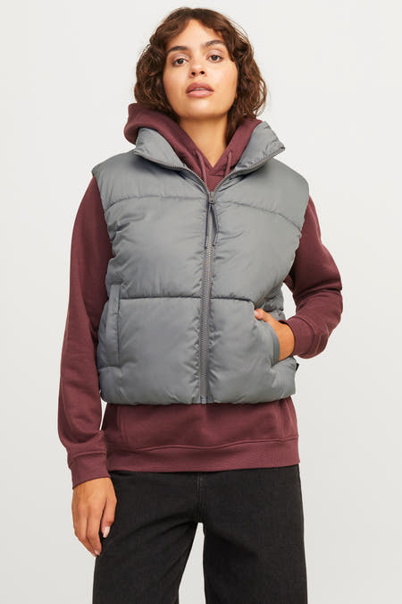 Grijze bodywarmer van JJXX, gedragen over een bordeauxrode hoodie en zwarte jeans.
