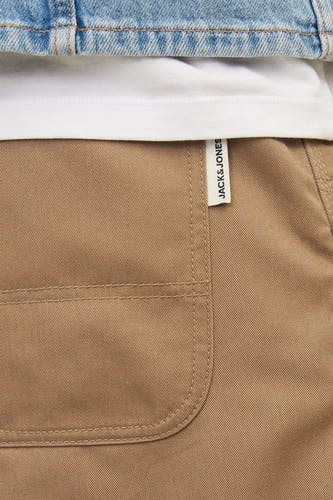 Beige broek van JACK & JONES JEANS INTELLIGENCE, met een label aan de zijkant en een afgeronde zak.
