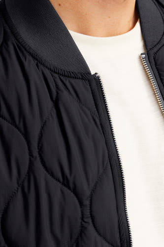 Zwarte korte jas van PREMIUM BLUE by JACK & JONES, met gewatteerd ruitpatroon en een zilverkleurige ritssluiting.
