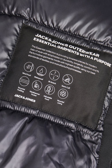 Zwarte lange jas van CORE BY JACK & JONES, met informatie over de eigenschappen op een label.

