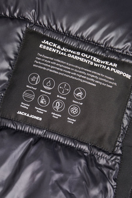 Zwarte lange jas van CORE BY JACK & JONES, met informatie over de eigenschappen op een label.
