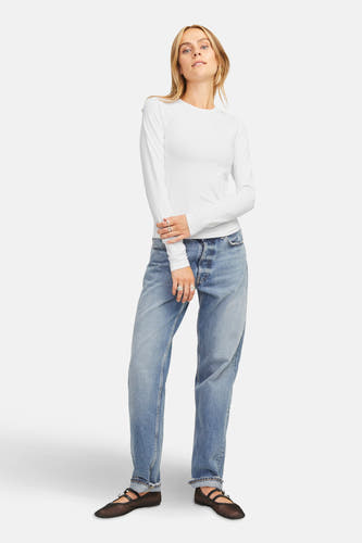 Wit T-shirt met lange mouwen van JJXX, gedragen met jeans en zwarte ballerina's, staand voor een witte achtergrond.

