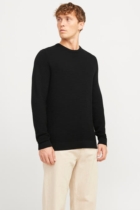 Zwarte trui met ronde hals van CORE BY JACK & JONES, met een horizontale ribtextuur, gedragen met een beige broek.
