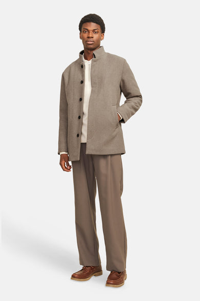 Lange beige jas van PREMIUM by JACK & JONES, met bijpassende pantalon en bruine schoenen.