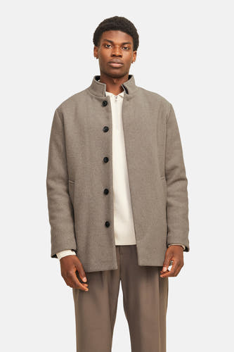 Beige lange jas van PREMIUM by JACK & JONES, met knoopsluiting en een witte trui eronder.
