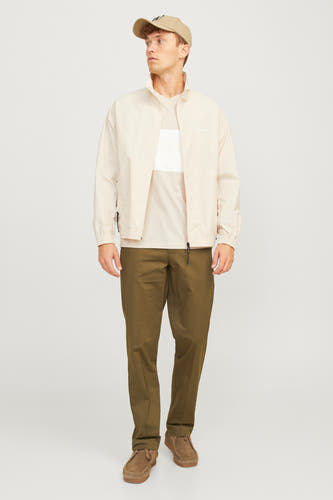Beige T-shirt met korte mouwen van CORE BY JACK & JONES, gedragen onder een beige jas met khaki broek en suède schoenen.
