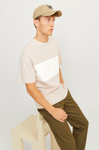 Beige T-shirt met korte mouwen van CORE BY JACK & JONES, gedragen met olijfgroene broek en pet met logo.
