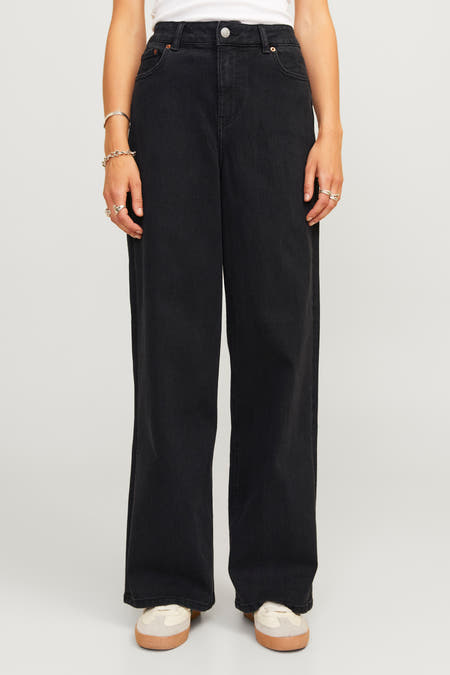 Zwarte denim jeans van JJXX, met wijde pijpen en zilveren sieraden om de polsen.
