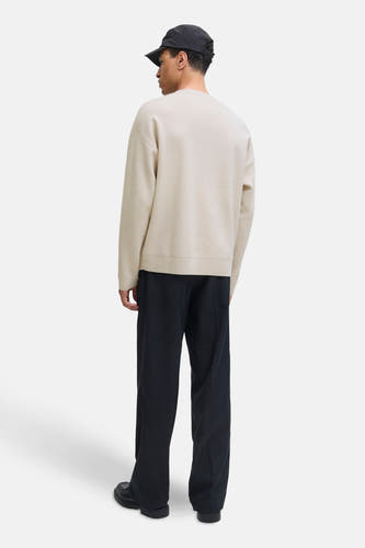 Beige trui met ronde hals van PREMIUM by JACK & JONES, achterkant gezien, met zwarte broek en pet.
