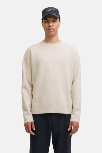 Beige trui met ronde hals van PREMIUM by JACK & JONES, gedragen met een zwarte pet en zwarte broek.