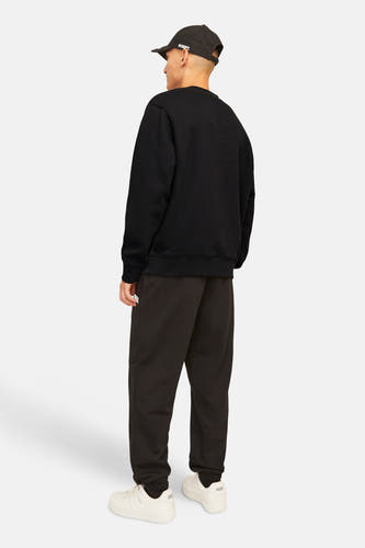 Zwarte sweater met ronde hals van ORIGINALS BY JACK & JONES, achterkant gezien, gecombineerd met een zwarte pet en bruine joggingbroek.
