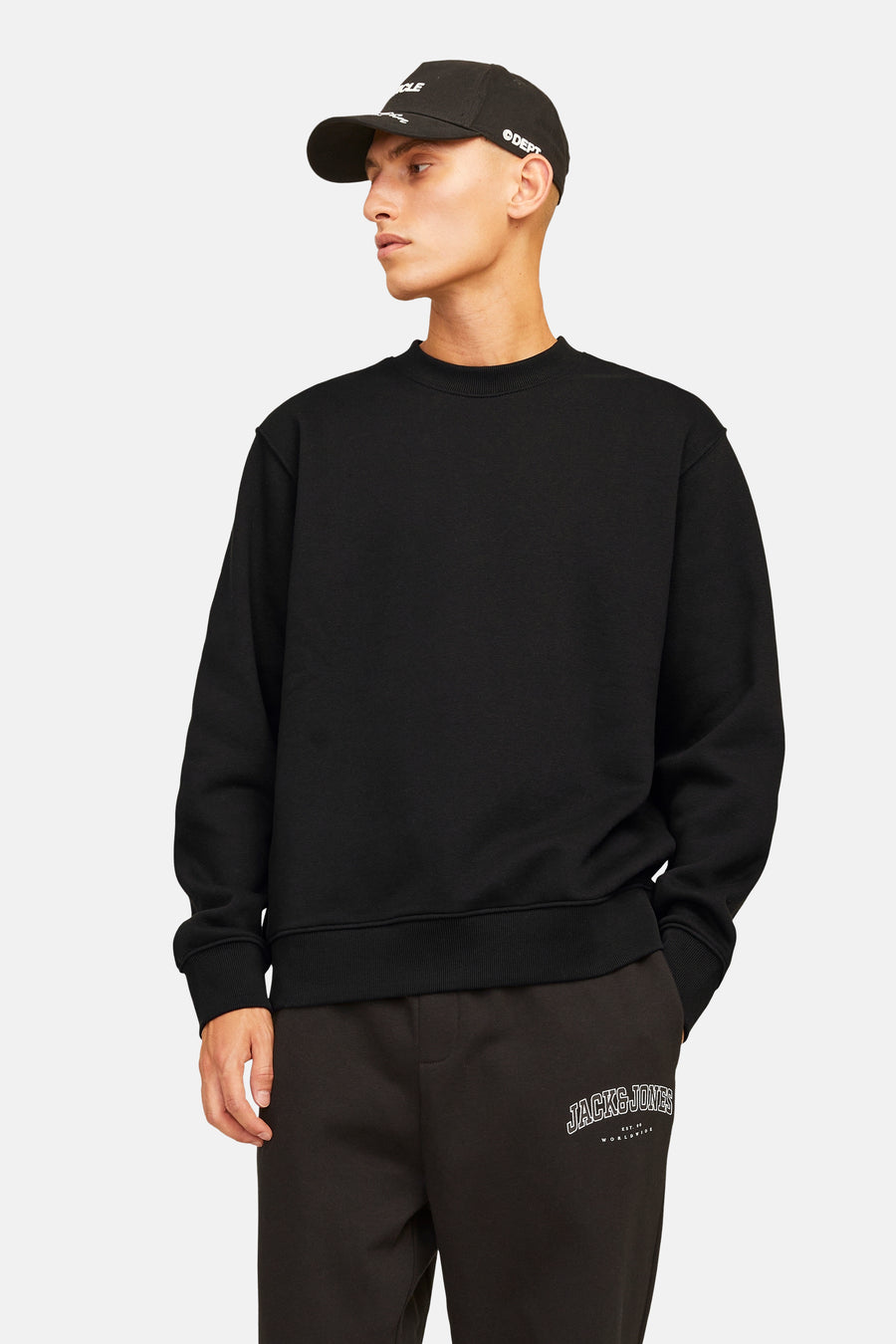 Zwarte sweater van ORIGINALS BY JACK & JONES, met lange mouwen en ronde hals, gedragen met joggingbroek en pet.