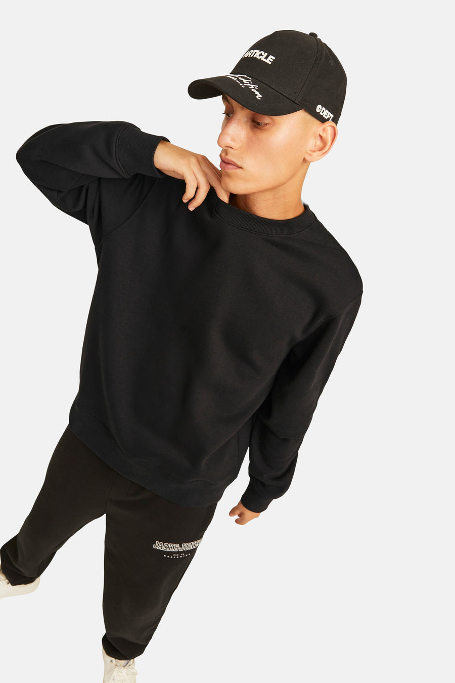 Zwarte sweater met ronde hals van ORIGINALS BY JACK & JONES, gedragen met een zwarte pet en zwarte joggingbroek.