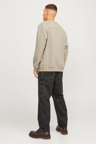 Man achterkant, grijze trui, zwarte broek, bruine schoenen.