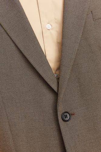 Grijs blazer van PREMIUM by JACK & JONES, met een subtiel patroon en een enkele knoop, gedragen over een lichtgekleurd overhemd.