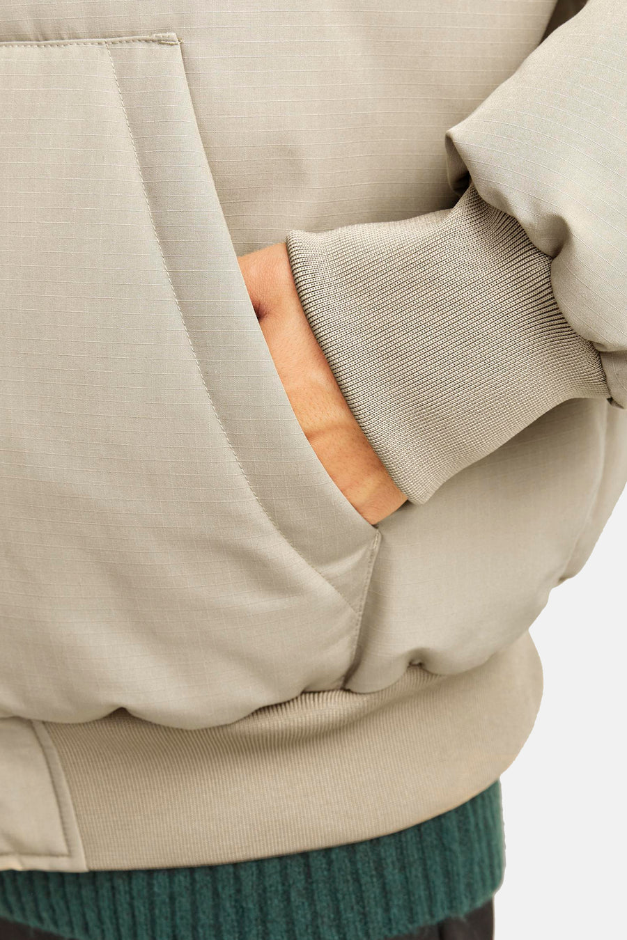 Beige korte jas van CORE BY JACK & JONES met ripstop-textuur, geribde boorden en hand in zak, gedragen over een groene trui.