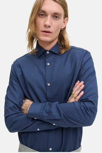 Chemise bleue à manches longues de PREMIUM by JACK & JONES, avec un motif subtil et des bras croisés.