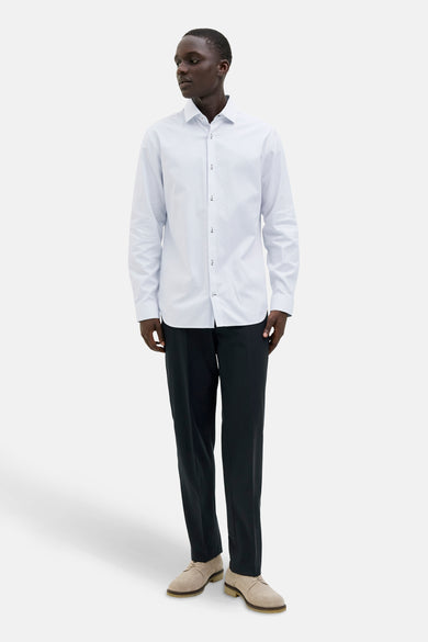 Chemise blanche à manches longues de PREMIUM by JACK & JONES, avec un fin motif rayé, portée avec un pantalon noir et des chaussures en cuir de mouton.