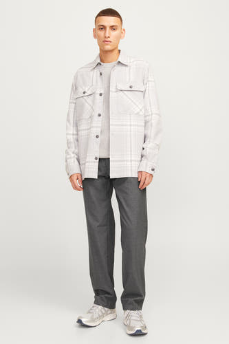 Grijze kostuumbroek van JACK & JONES JEANS INTELLIGENCE, gecombineerd met een lichtgrijze trui en zilveren sneakers.