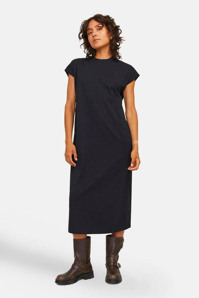 Robe noire avec des manches courtes de JJXX, portée avec des bottes brunes.
