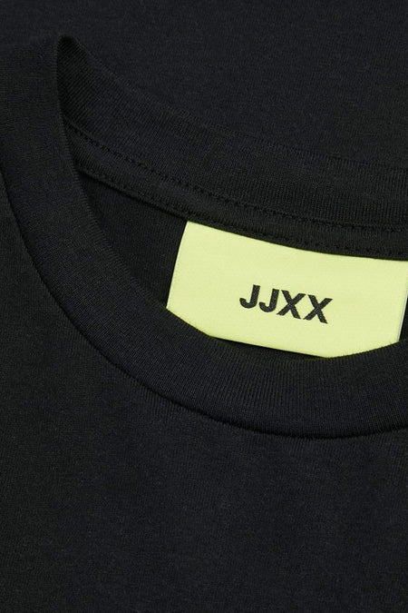 Zwarte jurk met korte mouwen van JJXX, close-up van de halslijn met een lichtgele merklabel.
