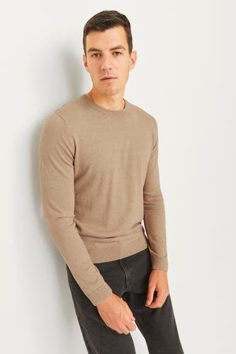 Pull beige à col rond de JJREBEL, avec des manches longues et un homme en pantalons foncés.