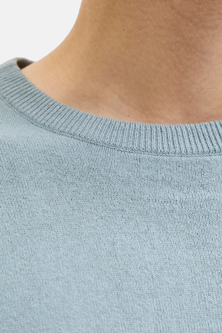 Pull bleu à col rond de JJREBEL, gros plan sur l'encolure et l'épaule.