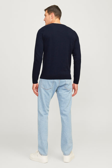 Blauwe trui met ronde hals van JJREBEL, op de rug gezien, gecombineerd met lichtblauwe jeans en witte sneakers.