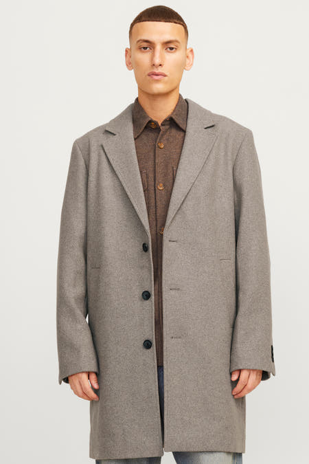 Lange ecru jas van PREMIUM by JACK & JONES, met knoopsluiting, over een bruin overhemd.